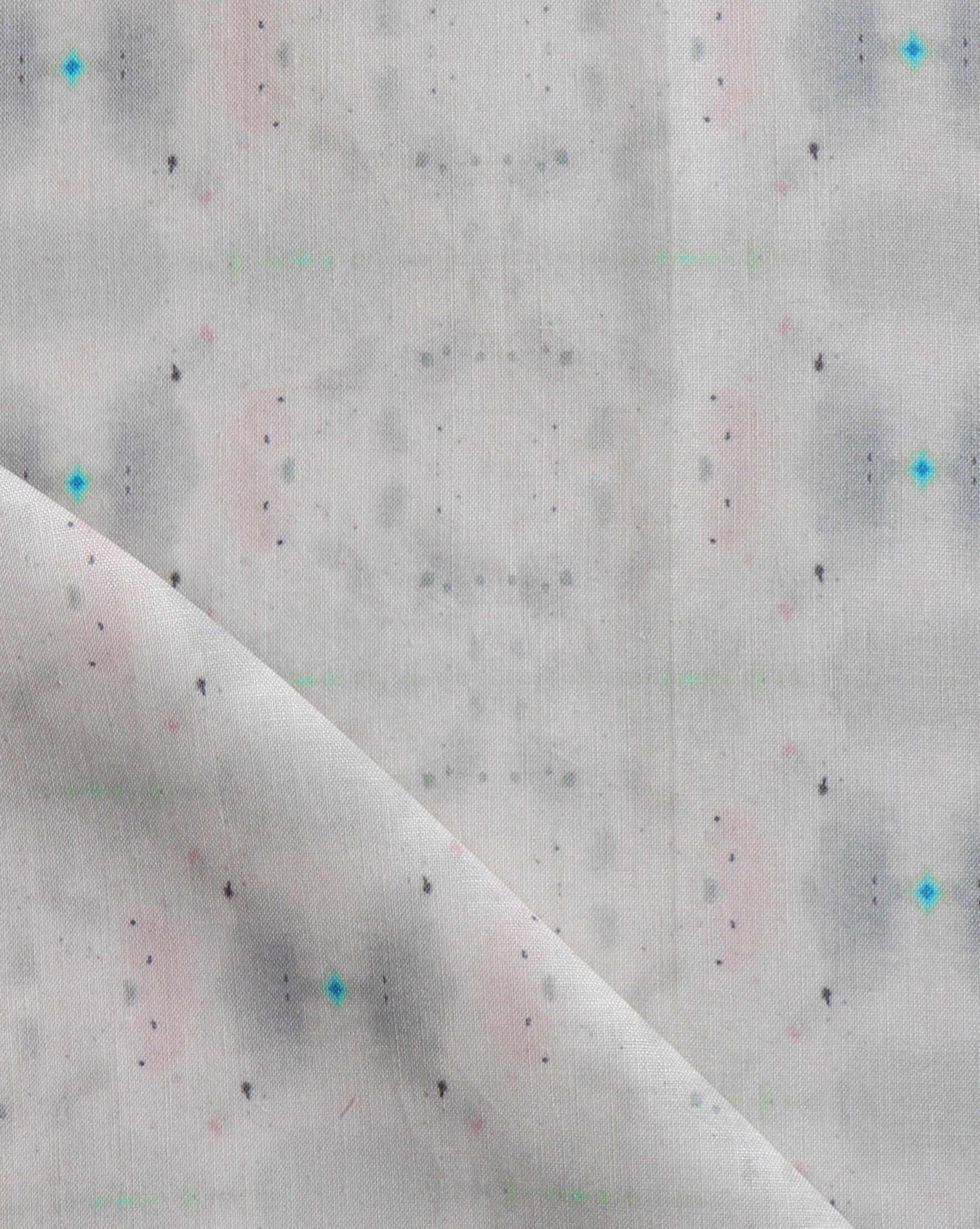 Detail of draped fabric yardage in a repeating ink blot print in shades of gray with turquoise and pink accents.