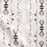 Detail of draped fabric yardage in a watercolor ikat stripe print in shades of cream, pink and gray on a white field.