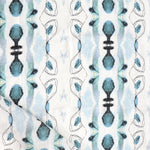 Detail of draped fabric yardage in a watercolor ikat stripe print in shades of blue and gray on a white field.