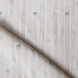 Detail of draped fabric in a painterly stripe print in light pink on a white field.