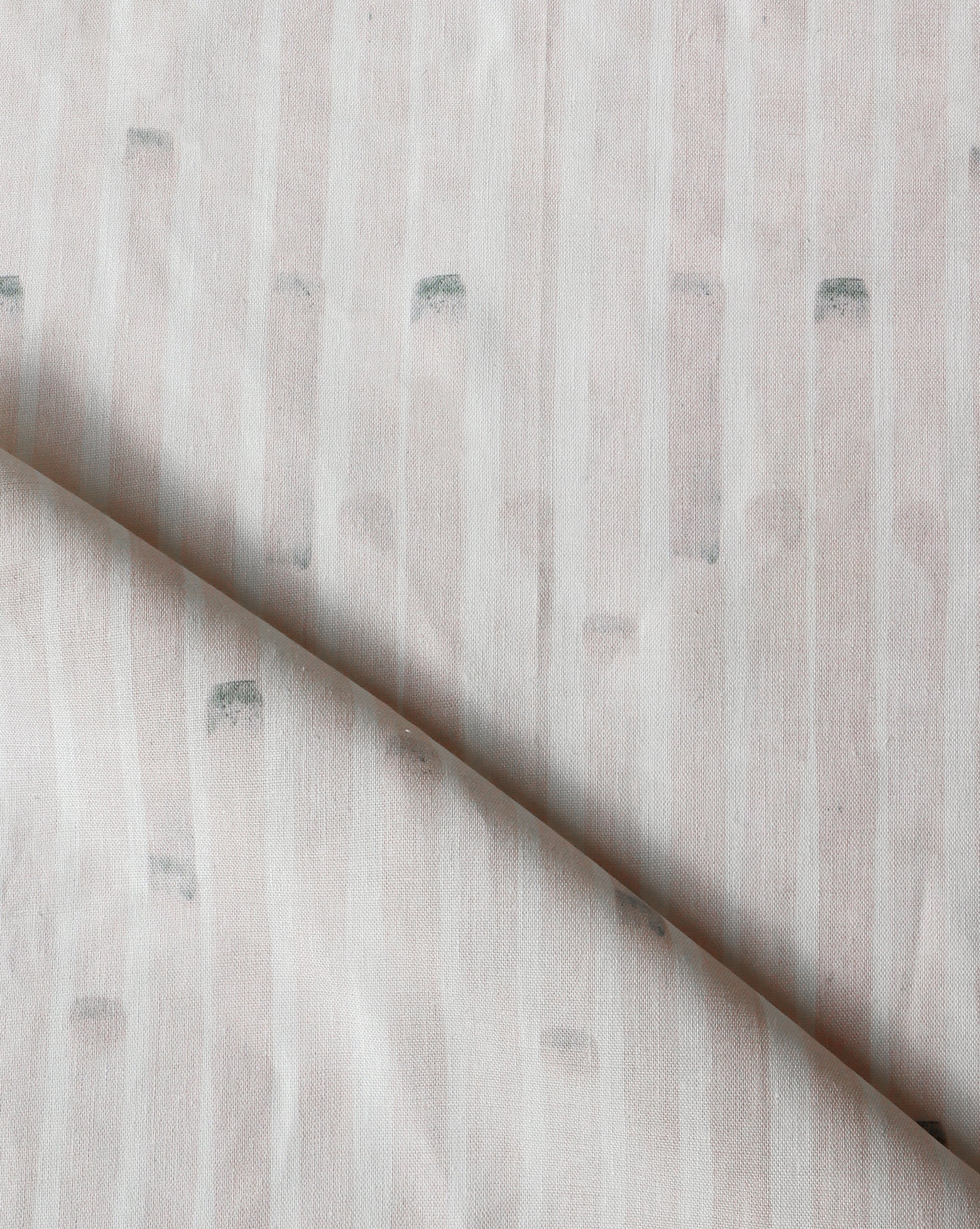 Detail of draped fabric in a painterly stripe print in light pink on a white field.