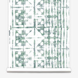Partially unrolled wallpaper yardage in a watercolor dyed grid print in mottled white and green.