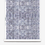Partially unrolled wallpaper yardage in a watercolor dyed grid print in mottled purple.