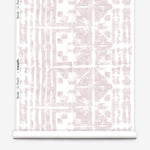 Partially unrolled wallpaper yardage in a watercolor dyed grid print in mottled white and pink.