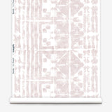 Partially unrolled wallpaper yardage in a watercolor dyed grid print in mottled white and pink.