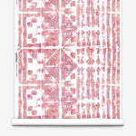 Partially unrolled wallpaper yardage in a watercolor dyed grid print in mottled white, pink and red.