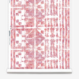Partially unrolled wallpaper yardage in a watercolor dyed grid print in mottled white, pink and red.