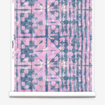 Partially unrolled wallpaper yardage in a watercolor dyed grid print in mottled pink and navy.