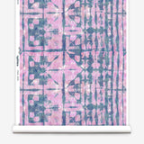 Partially unrolled wallpaper yardage in a watercolor dyed grid print in mottled pink and navy.