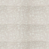 Detail of fabric in a batik splatter print in cream on a light gray field.
