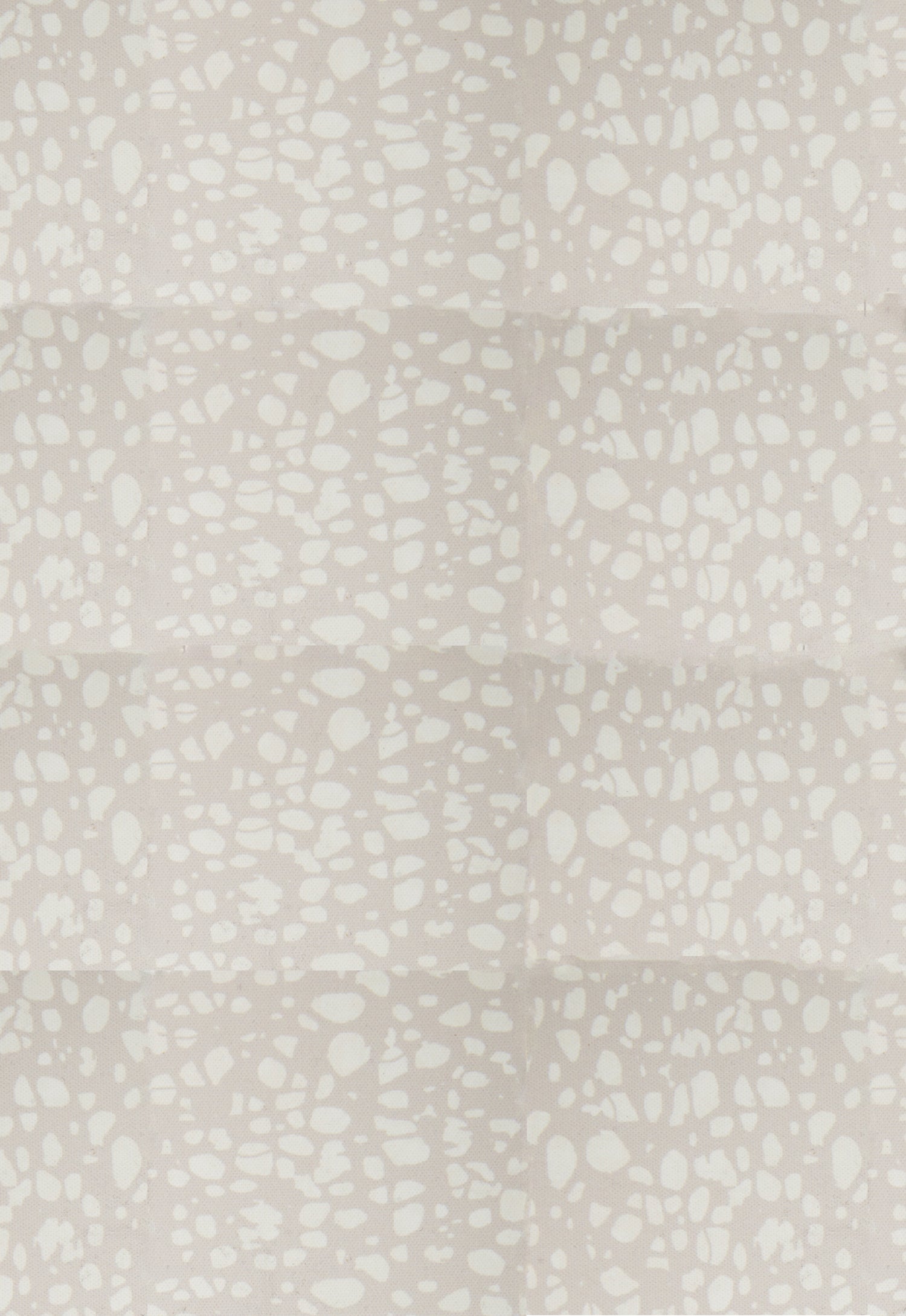 Detail of fabric in a batik splatter print in cream on a light gray field.