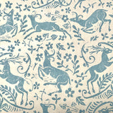 Detail of wallpaper in a deer, leaf and flower print in blue-gray on a mottled tan field.