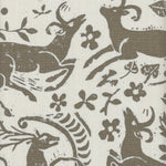 Close-up of fabric in a deer, leaf and flower print in taupe on a cream field.