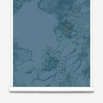 Partially unrolled wallpaper yardage in a painterly floral print in shades of navy and yellow on a blue field.