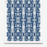 Partially unrolled wallpaper yardage in a painterly ikat print in blue and white.