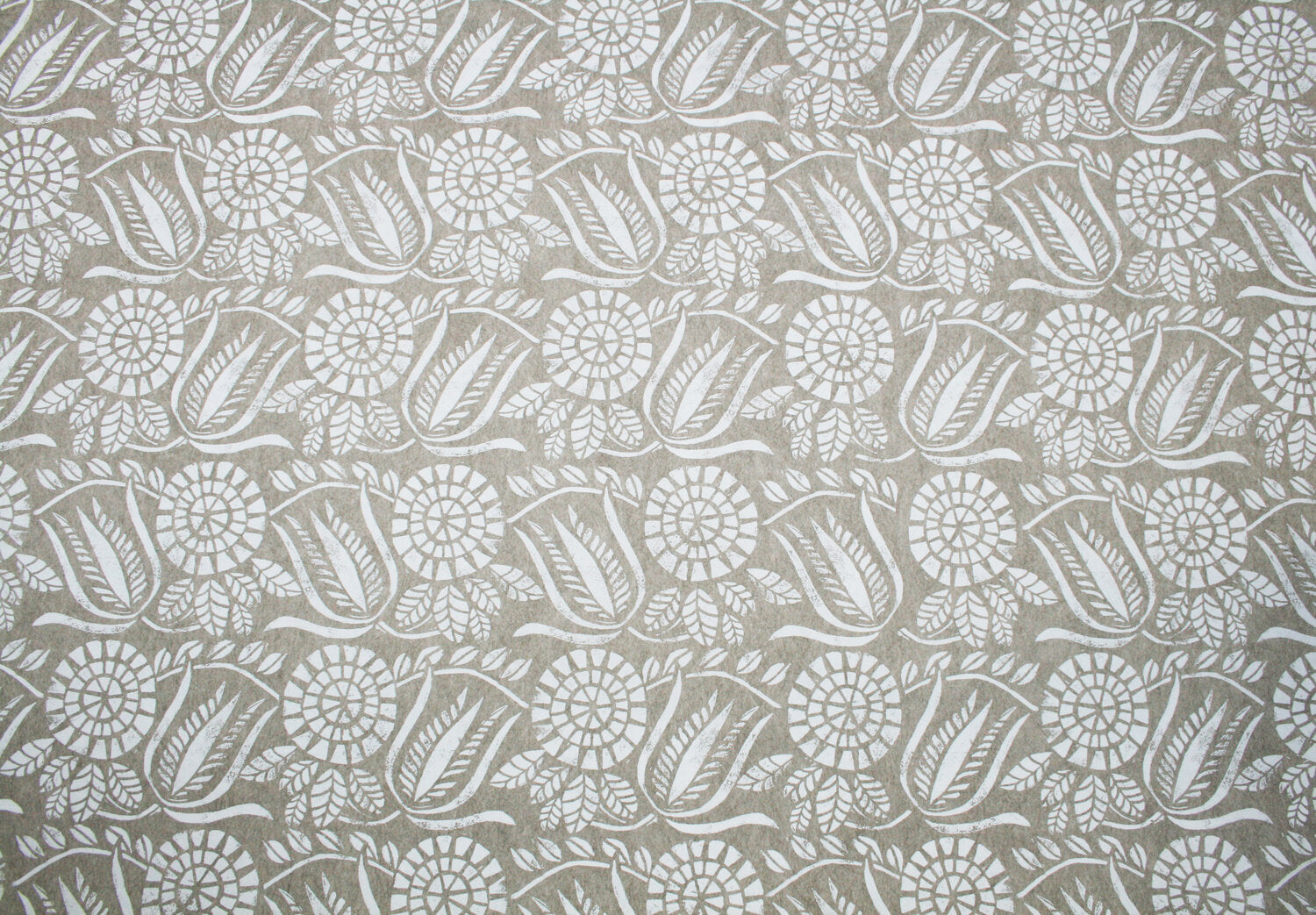 Detail of wallpaper in a dense floral print in white on a tan field.
