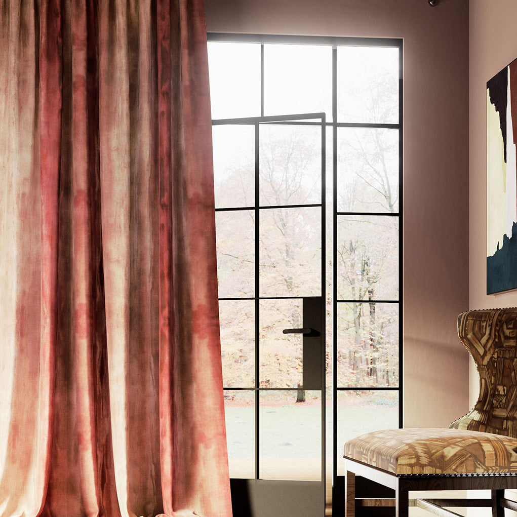 Airy room with a glass door framed in black trim and long curtains in a watery pale-red paint pattern.