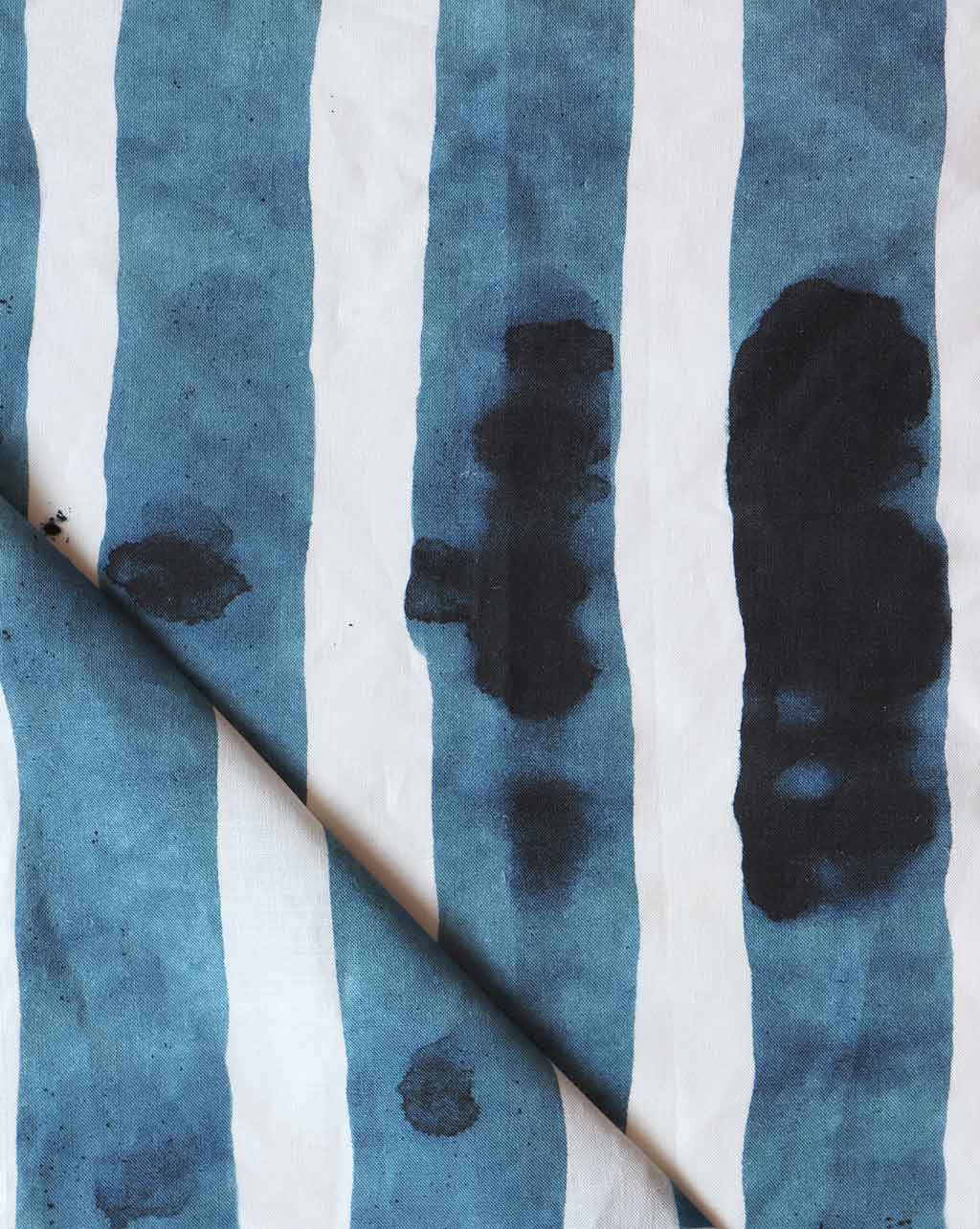 Folded printed linen with bold watercolor stripes in inky blue and white. 