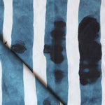 Folded printed linen with bold watercolor stripes in inky blue and white. 