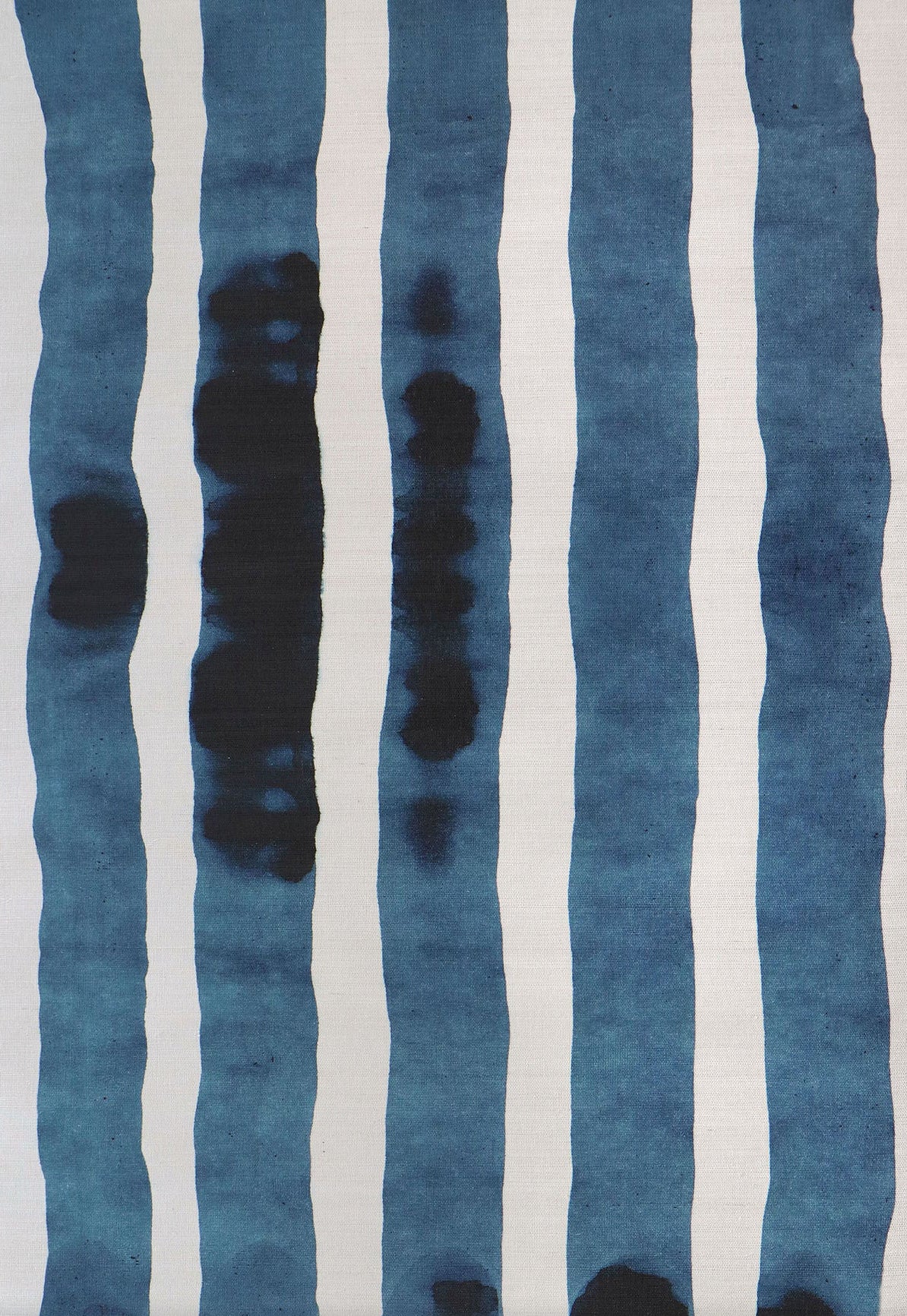 Grasscloth Wallpaper close up with bold watercolor stripes in inky blue and white. 
