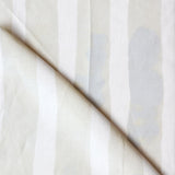 Folded printed linen with bold watercolor stripes in cream and white. 