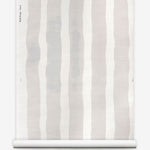 Grasscloth wallpaper roll with bold watercolor stripes in beige and white on a white background.