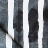 Folded printed linen with bold watercolor stripes in black and white. 