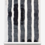 Grasscloth Wallpaper roll with bold watercolor stripes in black and white on a white background. 