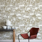 A modernist armchair stands in front of a wall papered in a painterly palm tree print in shades of gray, gold and white.