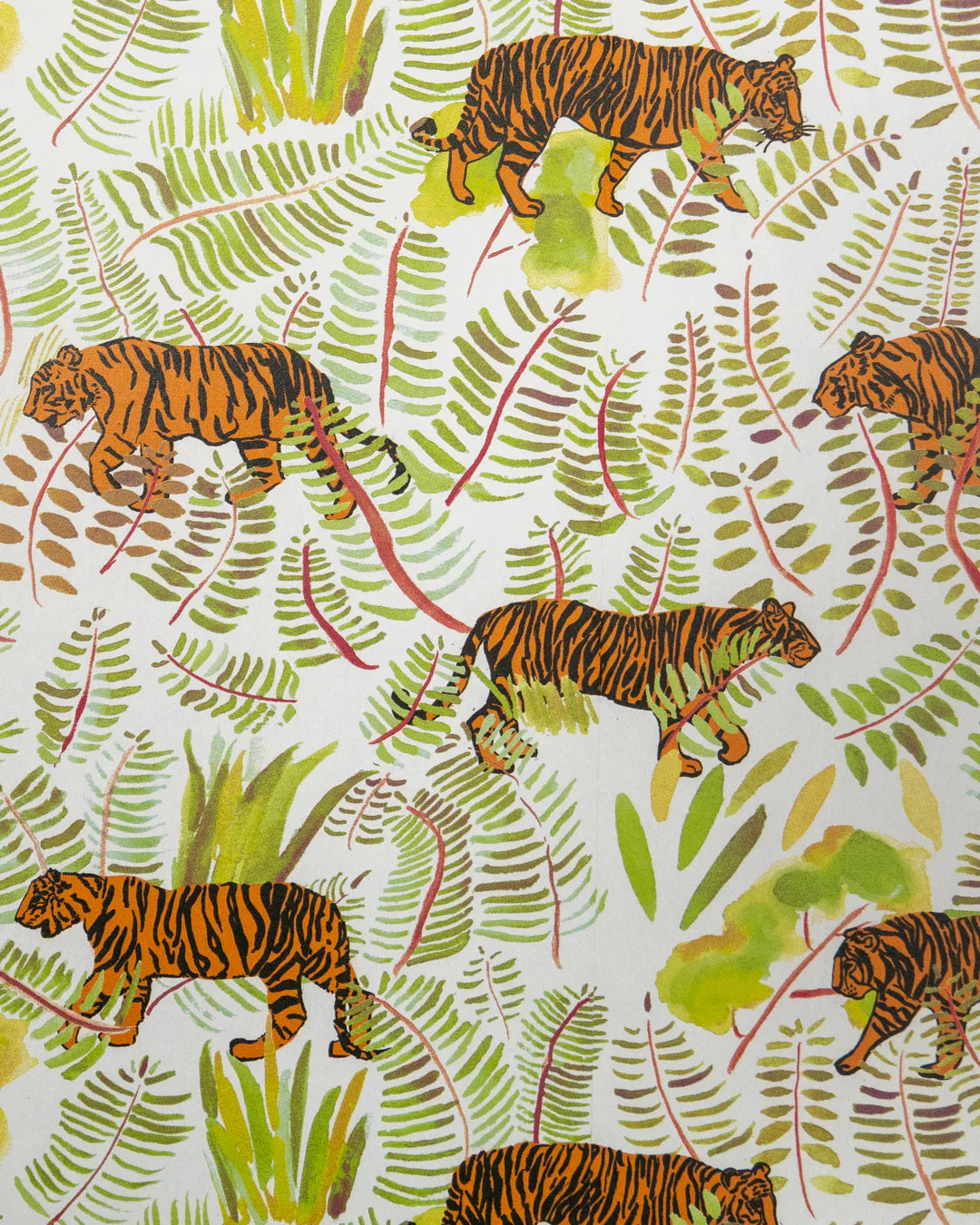 Detail of wallpaper in a playful tiger and leaf print in shades of green, orange and black on a white field.