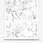 Partially unrolled wallpaper yardage in a watercolor painterly print in shades of gray, purple and cream.