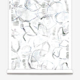 Partially unrolled wallpaper yardage in a watercolor painterly print in shades of gray, purple and cream.