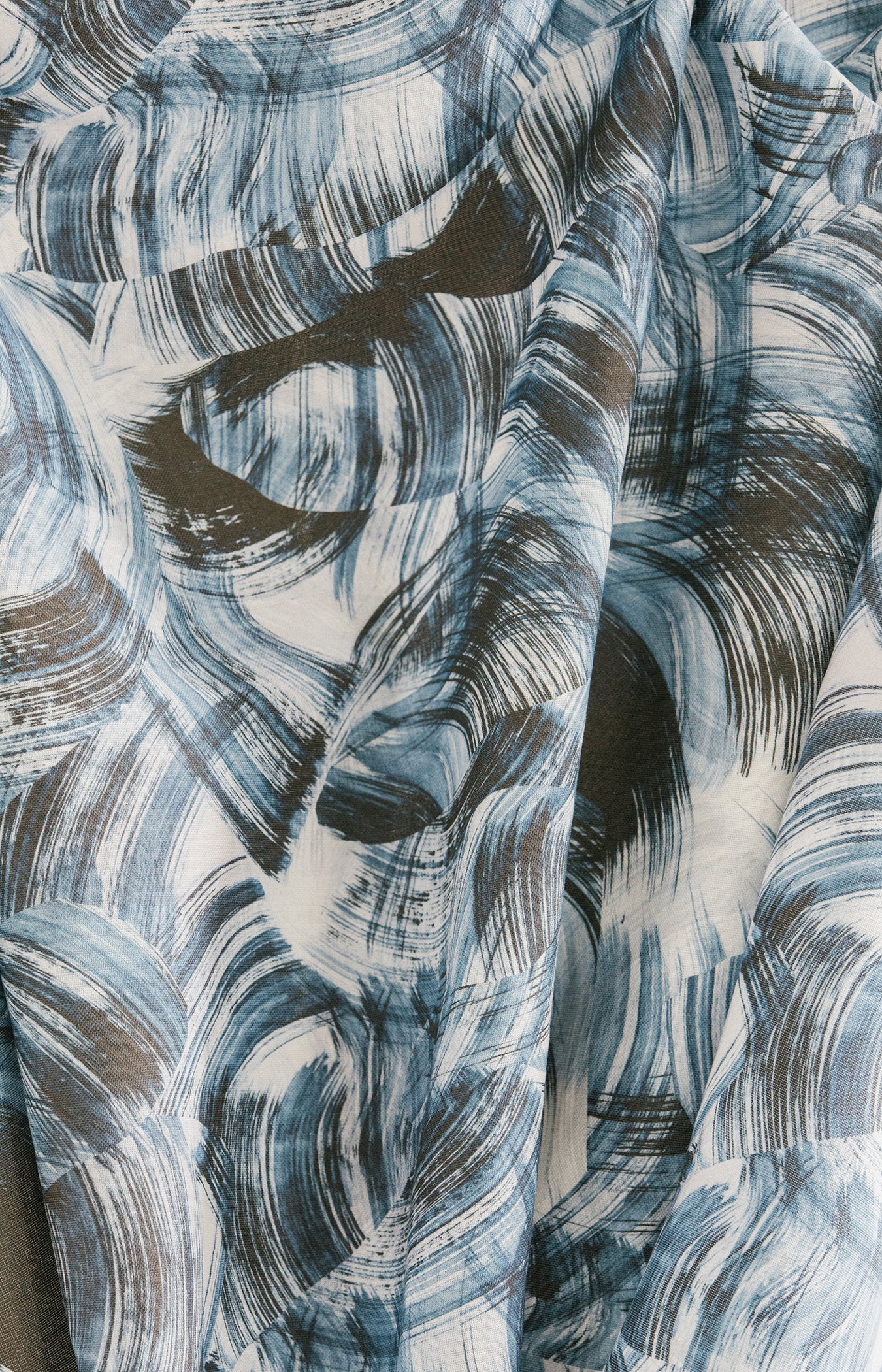 Draped fabric yardage in an absract paint swatch print in black and navy on a white field.