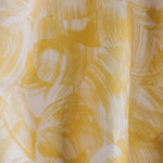 Draped fabric yardage in an absract paint swatch print in yellow on a white field.