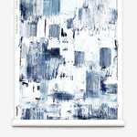 Partially unrolled wallpaper yardage in a watercolor textural print in shades of navy and blue on a white field.