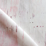 Detail of fabric in a watercolor paint blot print in light pink on a white field.