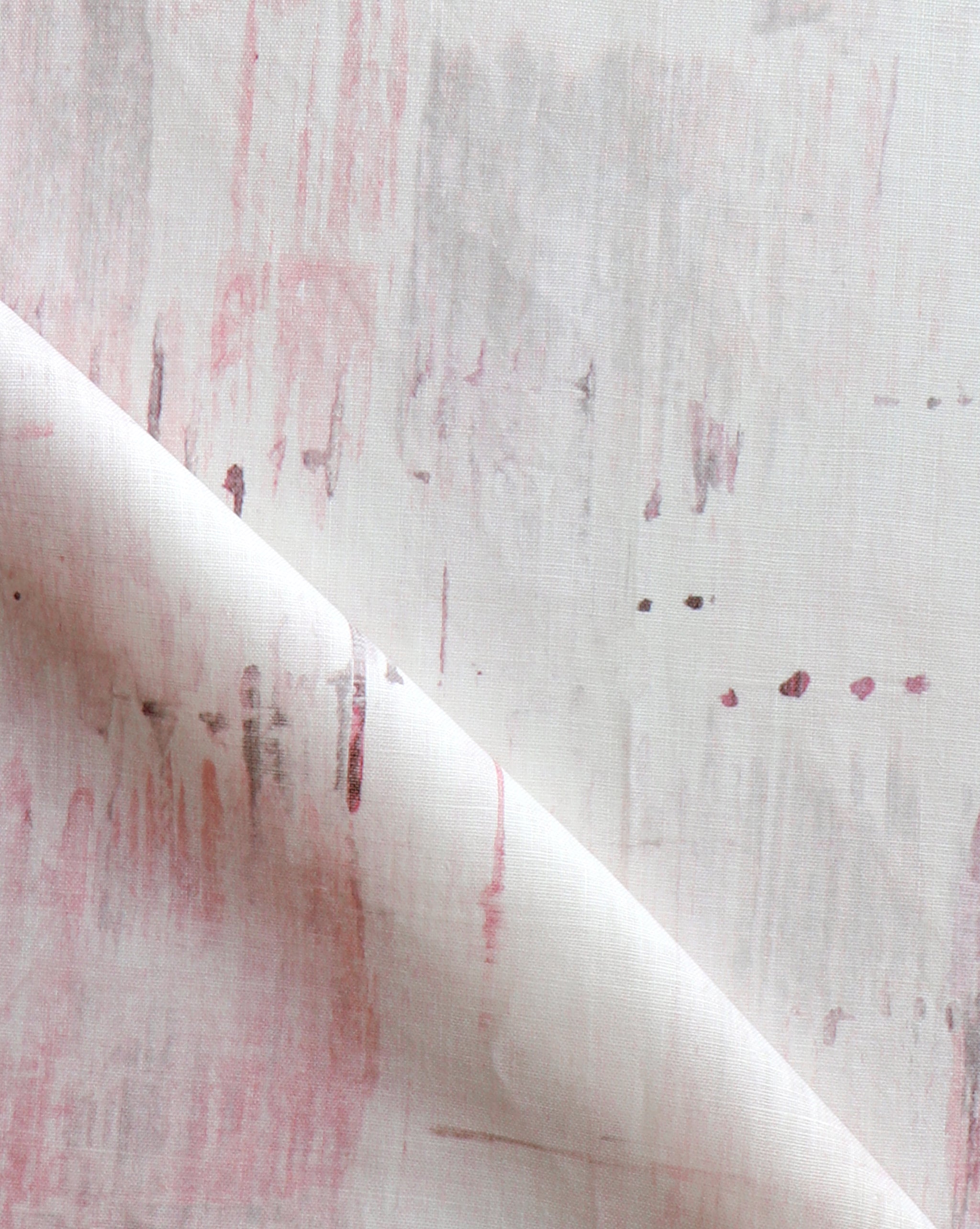 Detail of fabric in a watercolor paint blot print in light pink on a white field.