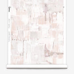Partially unrolled wallpaper yardage in a watercolor textural print in shades of pink, cream and tan.