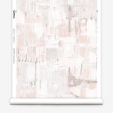 Partially unrolled wallpaper yardage in a watercolor textural print in shades of pink, cream and tan.
