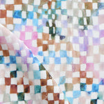 Detail of fabric in a painterly check pattern in shades of pink, brown and blue on a white field.