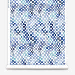 Partially unrolled wallpaper yardage in a painterly chess board print in shades of blue, navy and white.