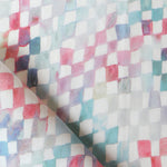 Detail of fabric in a painterly check pattern in shades of pink and turquoise on a white field.