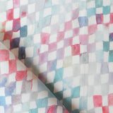 Detail of fabric in a painterly check pattern in shades of pink and turquoise on a white field.