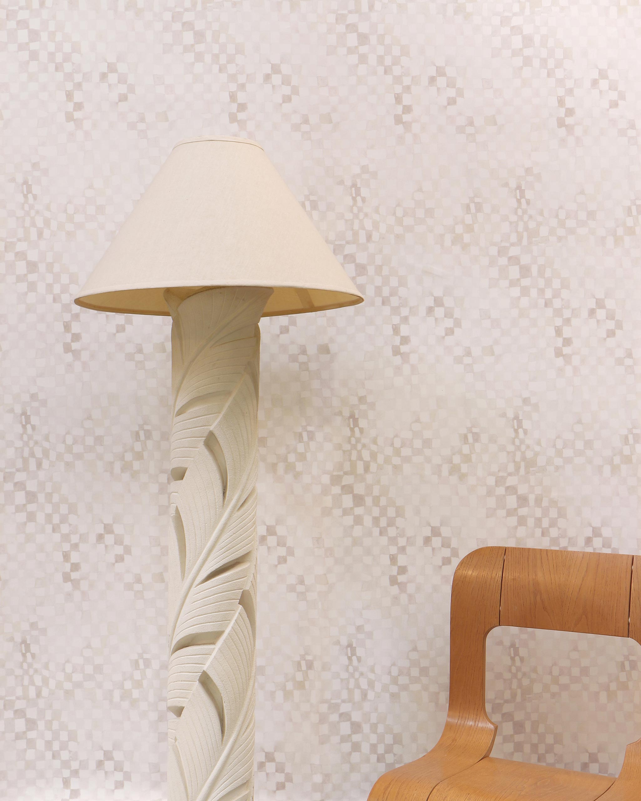 A modernist living tableau with a wall papered in a painterly chess board print in shades of cream and white.
