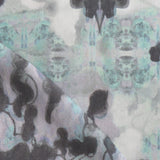 Detail of fabric in a watercolor tree print in shades of purple, turquoise and gray on a white field.