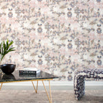 A modernist living tableau with a wall papered in a watercolor tree print in gray, peach, tan and white.