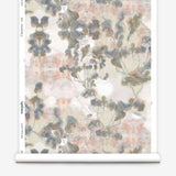 Partially unrolled wallpaper yardage in a watercolor tree print in gray, peach, tan and white.