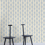 Two minimalist black chairs stand in front of a wall papered in a playful curvy stripe print in white, yellow and light blue.
