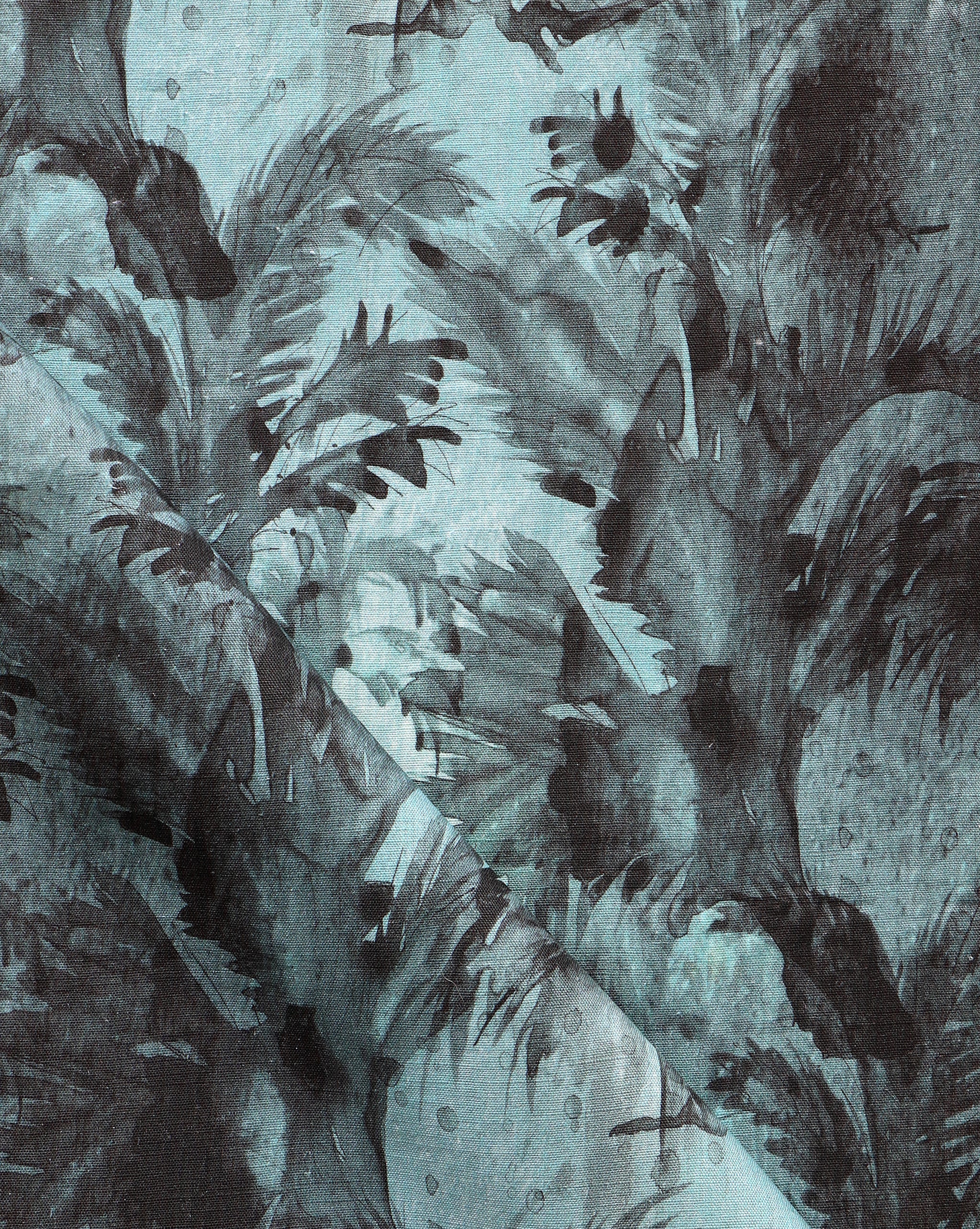 Detail of fabric in a painterly palm leaf print in shades of turquoise and gray.
