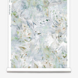 Partially unrolled wallpaper yardage in a watercolor painted print in shades of blue, green, yellow and white.